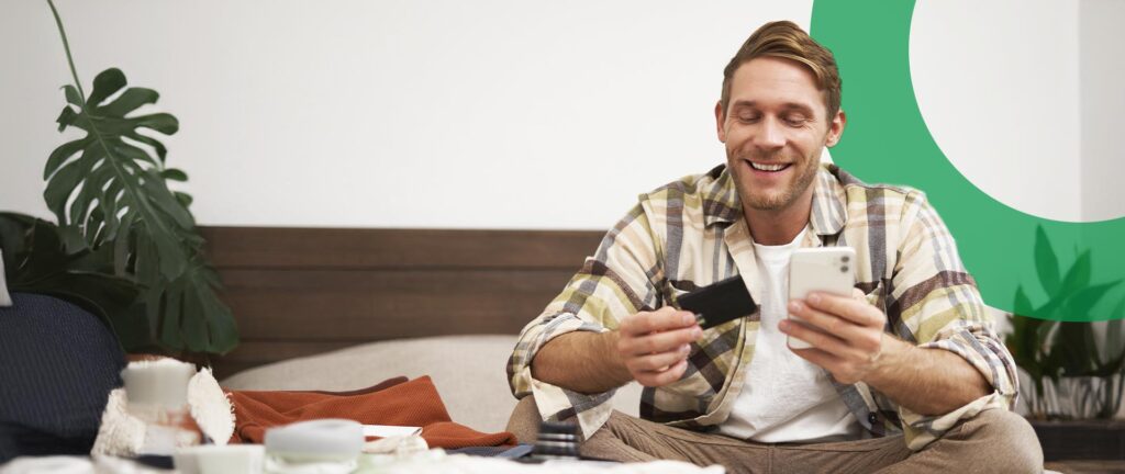 Smiling man looks at card and phone